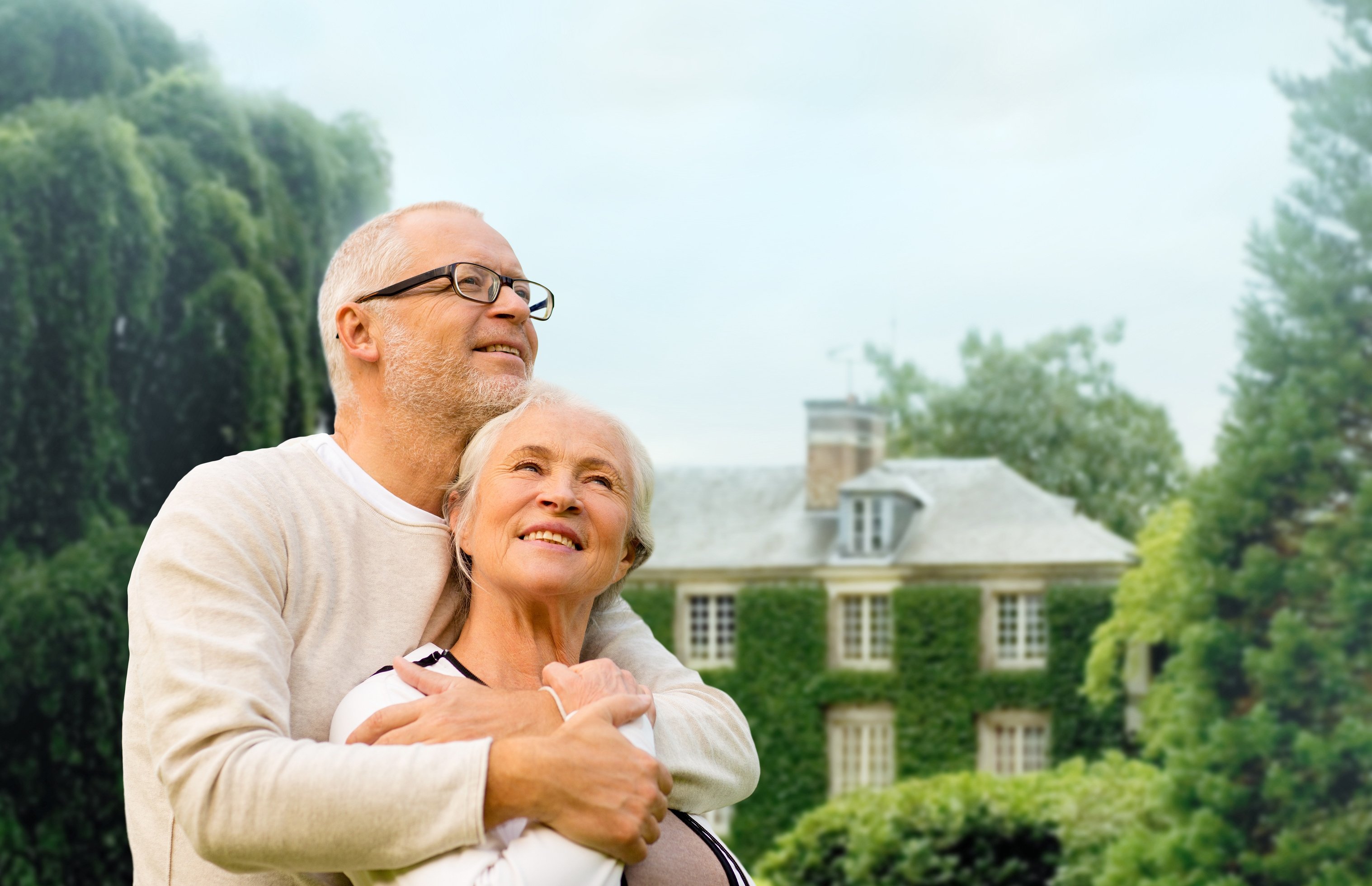 Senior Couple Hugging over Living House Background